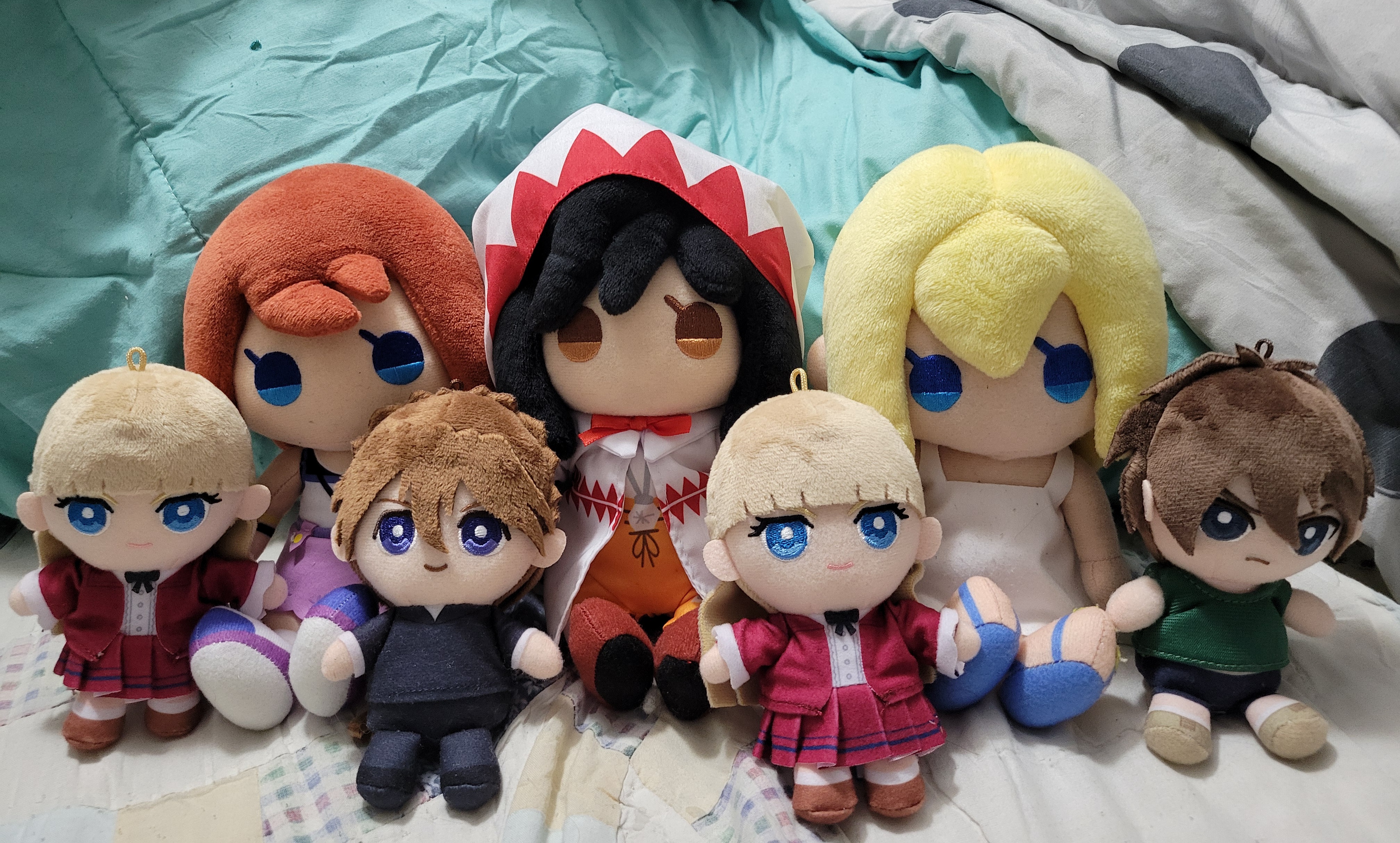 Namine, Relena, Duo, Relena, Heero, Garnet, and Kairi plushes sitting on a mattress.